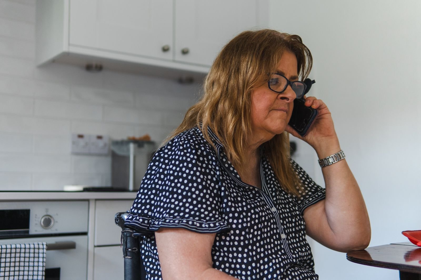 Le premier appel Femme au téléphone dans sa cuisine, en train d'expliquer une situation.