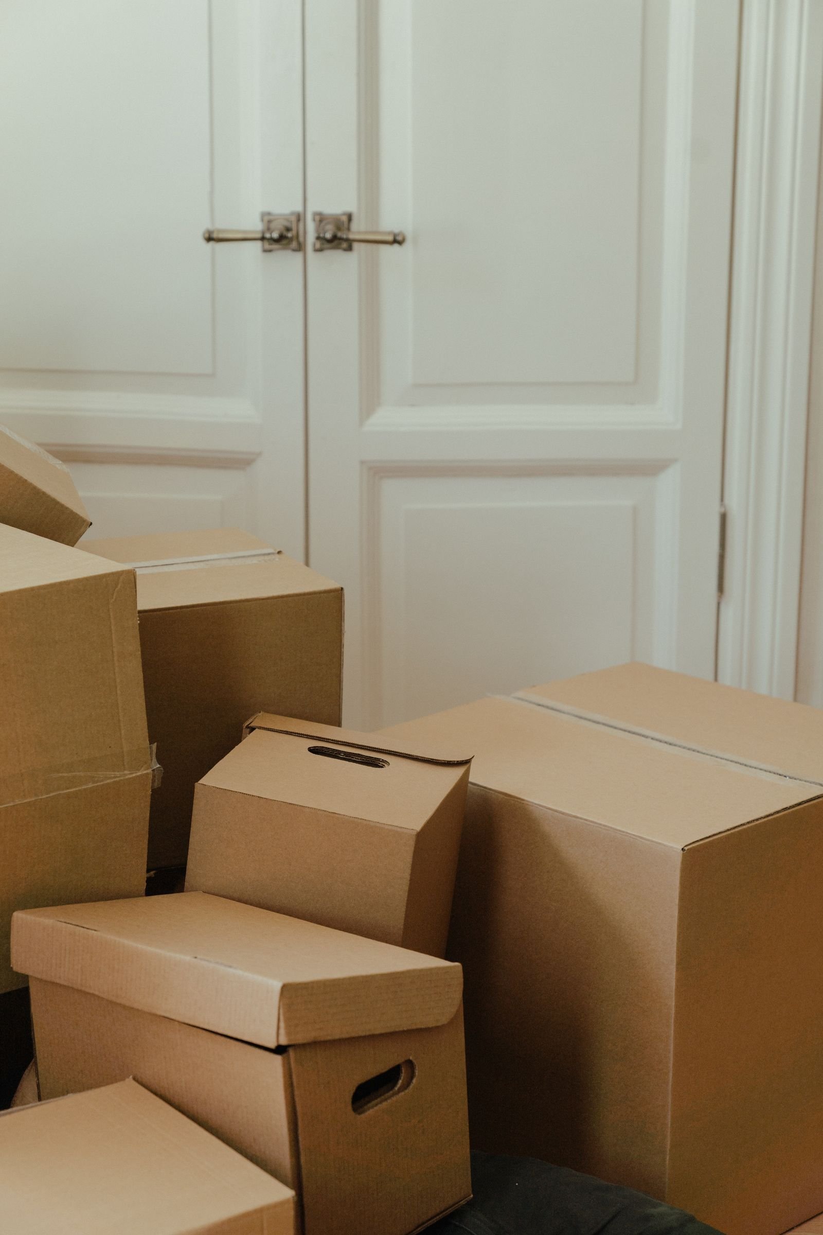 Cartons préparés pour l'évacuation Cartons de déménagement fermés et empilés contre une porte, prêts à être évacués.